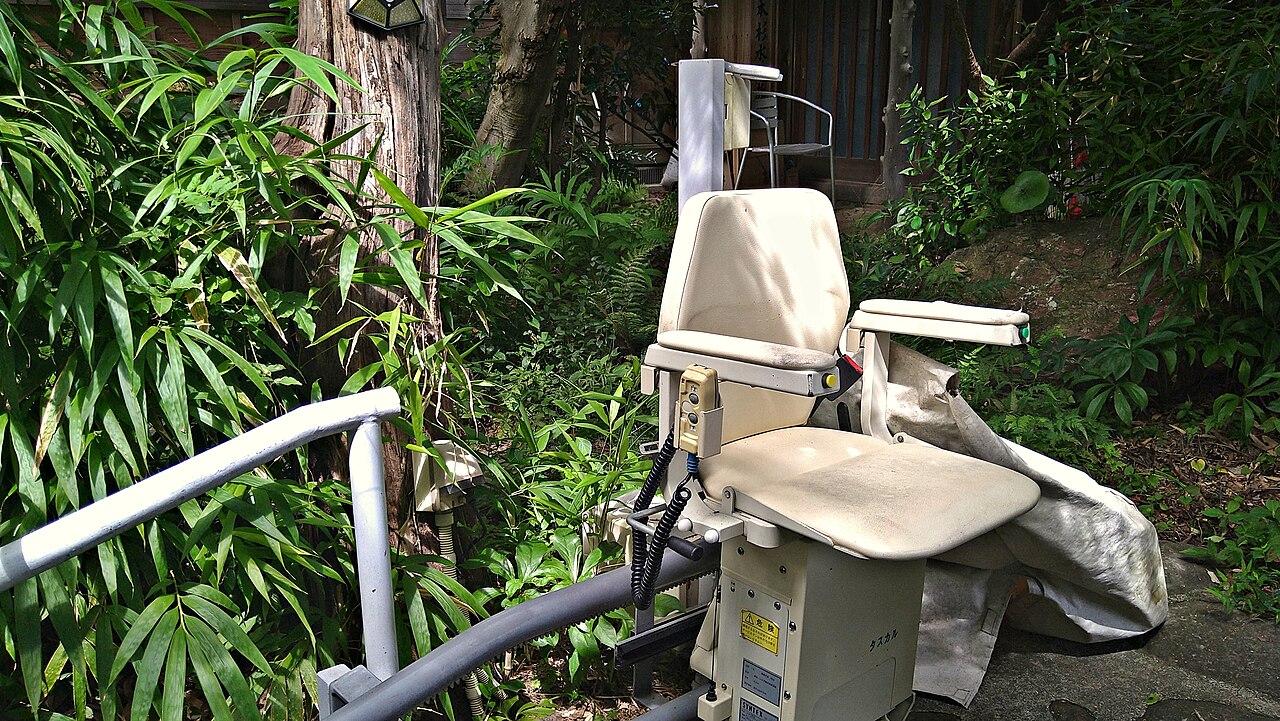 Real outdoor chairlift with seat, armrests and footrest beside garden steps in Japan